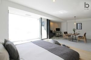 a bedroom with a large white bed and a living room at b hotel Heiwaodori 1002 - High Rise Apt Famous Hiroshima dori 6ppl in Hiroshima