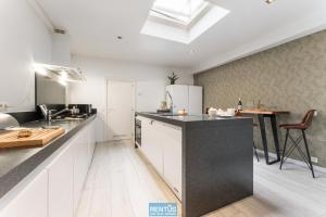 a kitchen with white cabinets and a black counter top at Maison La Roussette - in the heart of Nieuwpoort in Nieuwpoort +14 photos