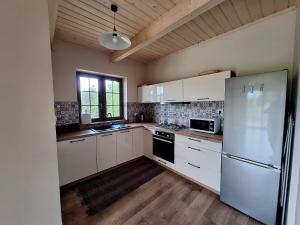 a kitchen with white cabinets and a refrigerator at Domek w Klisiówkach in Ujsoły