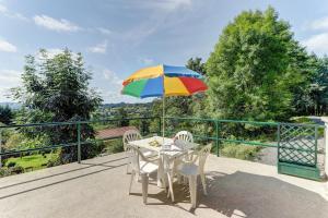 a table with a colorful umbrella on a balcony at Les Bois Noirs - appt vue montagne in Arconsat