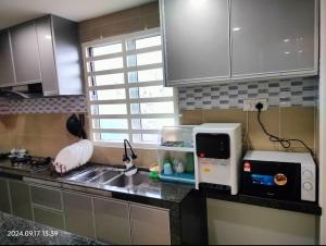a kitchen with a counter with a sink and a microwave at DARUL AMAN Homestay Jitra in Jitra