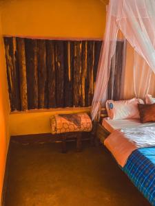 a bedroom with two beds and a bench in it at Sipi Falls Lodge in Sipi