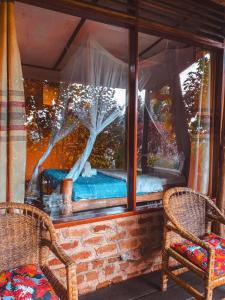 a room with two chairs and a bed in a window at Sipi Falls Lodge in Sipi
