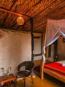 a bedroom with a bed and a chair and a table at Sipi Falls Lodge in Sipi