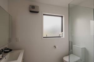a white bathroom with a toilet and a window at Beating Heart of Christchurch in Christchurch +19 photos