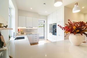 a kitchen with white cabinets and a vase with flowers on a counter at Solar do Ilheuzinho in Câmara de Lobos