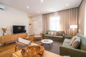 a living room with couches and a flat screen tv at Solar do Ilheuzinho in Câmara de Lobos