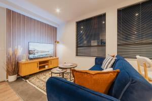 a living room with a blue couch and a tv at Fitzgerald Focus - Your 1BR Urban Oasis in Christchurch