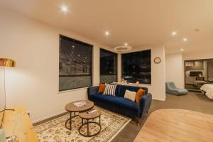 a living room with a blue couch and some windows at Fitzgerald Focus - Your 1BR Urban Oasis in Christchurch