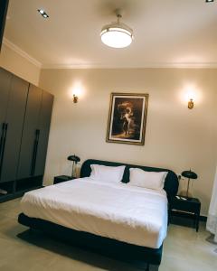a bedroom with a white bed with a picture on the wall at Kipepeo Apartments in Nkongontha +29 photos