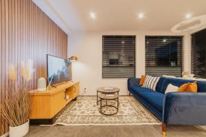 a living room with a blue couch and a tv at Cashel Grandeur - Luxurious 4-Bedroom Home in Christchurch