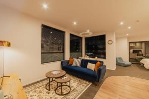 a living room with a blue couch and some windows at Cashel Grandeur - Luxurious 4-Bedroom Home in Christchurch