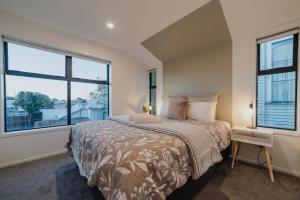 クライストチャーチにあるMisty Meadows Manor - Your Urban Oasisの大きなベッドと2つの窓がある寝室