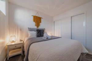 a white bedroom with a bed and a night stand at The Hagley Park Stunna in Christchurch
