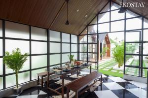 a dining room with a table and large windows at EKOSTAY - Oakwood Chalet in Alibaug
