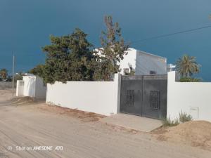 a white building with a door on the side of a road at Maison la rose 2 chambres in Mezraya