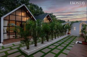 a house with a row of palm trees in front of it at EKOSTAY - Oakwood Chalet in Alibaug +15 photos