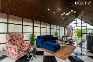 a living room with a blue couch and chairs at EKOSTAY - Oakwood Chalet in Alibaug