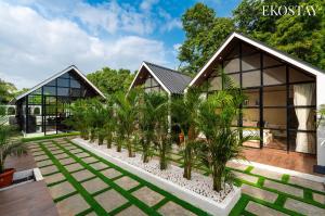 a house with a row of palm trees in front of it at EKOSTAY - Oakwood Chalet in Alibaug