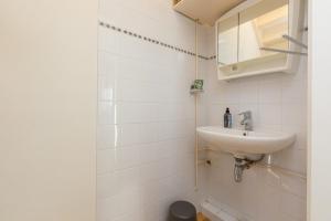 a white bathroom with a sink and a mirror at Welcome in - Vakantiewoning in het centrum met tuin en airco, Zoutelande in Zoutelande +18 photos