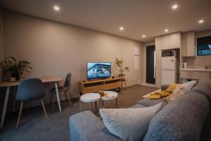 a living room with a couch and a table and a kitchen at Central City Paradise in Christchurch