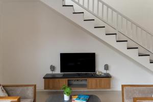 een woonkamer met een flatscreen-tv onder een trap bij Awila Villas Kuta by The Wina Resorts in Legian