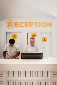 two people standing behind a counter with a laptop at Ryans La Marina in Ibiza Town