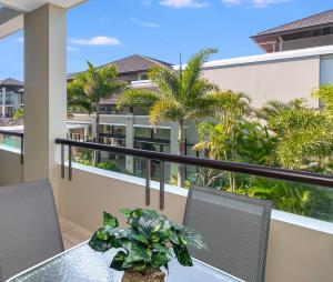a balcony with a table and chairs and palm trees at 208 Santai - Spacious Family Apartment by uHoliday in Casuarina