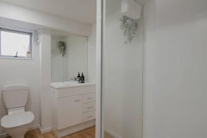 a white bathroom with a toilet and a window at The Dream Townhouse in Christchurch