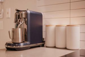 a juicer sitting on a counter next to three rolls of paper towels at Serene Spaces on Tuam - 2 Bedroom Apartment in Christchurch +30 photos