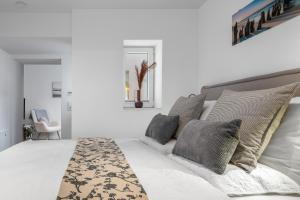a white bedroom with a large white bed with gray pillows at Leneshus in Flensburg