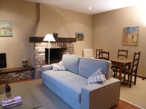 sala de estar con sofá azul y chimenea en Maison Chantraine, en Ramillies