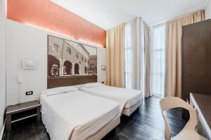 a hotel room with two beds and a desk at Hotel Milano Navigli in Milan
