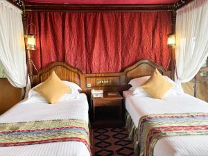 a bedroom with two beds and a red curtain at Kirawira Serena Camp in Handajega +34 photos