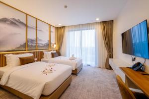 a hotel room with two beds and a flat screen tv at Betworld Casino & Hotel in Krong Poi Pet