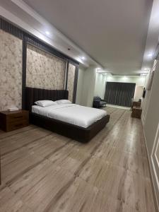a bedroom with a large bed and a wooden floor at itten plaza blue in Salalah