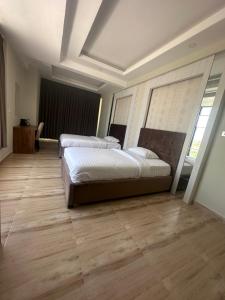 two beds in a large room with wooden floors at itten plaza blue in Salalah