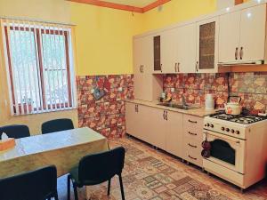a kitchen with a stove and a table with chairs at Paradise Guest House in Tsaghkadzor