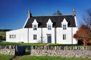 an old white house with a stone wall at Hillview Cottage in Glenlivet