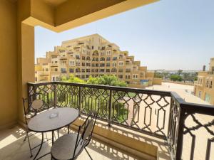 拉斯阿尔卡麦Hala Holiday Homes- Bab Al Bahr Residence, Al Marjan Island的阳台配有2张桌子和椅子,大楼