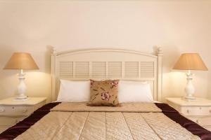 a bedroom with a large white bed with two lamps at Princess Resort, Santikos Collection in Agia Paraskevi
