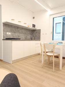 una cucina con mobili bianchi, tavolo e sedie di Loft Delitala 1 ad Alghero