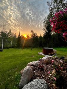 a sunset in a park with a bench and rocks at ARKA Puhkemajad in Päidre
