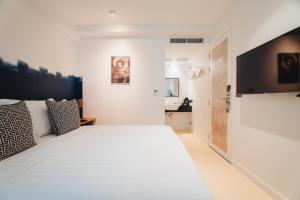 een witte slaapkamer met een groot bed en een televisie bij Xinlor House - Phuket Old Town in Phuket