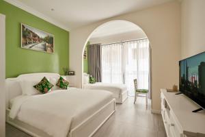 a bedroom with a white bed and a flat screen tv at Chez Mimosa Petite - Free Laundry in Ho Chi Minh City