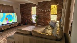 a living room with a couch and a flat screen tv at Big Holliday house with pool in Brisbane