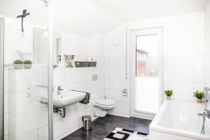 a white bathroom with a sink toilet and a tub at FEEL - Comfort Haus Münsterblick - Nahe Münster in Senden +24 photos