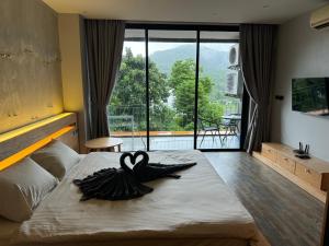 a bedroom with a large bed with a large window at ReLife NaiHarn Beach by Mill in Rawai Beach