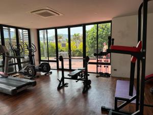 a gym with several tread machines and a woman in the background at ReLife NaiHarn Beach by Mill in Rawai Beach