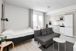 a bedroom with a bed and a couch and a kitchen at Hiisi Homes Kangasala in Suorama
